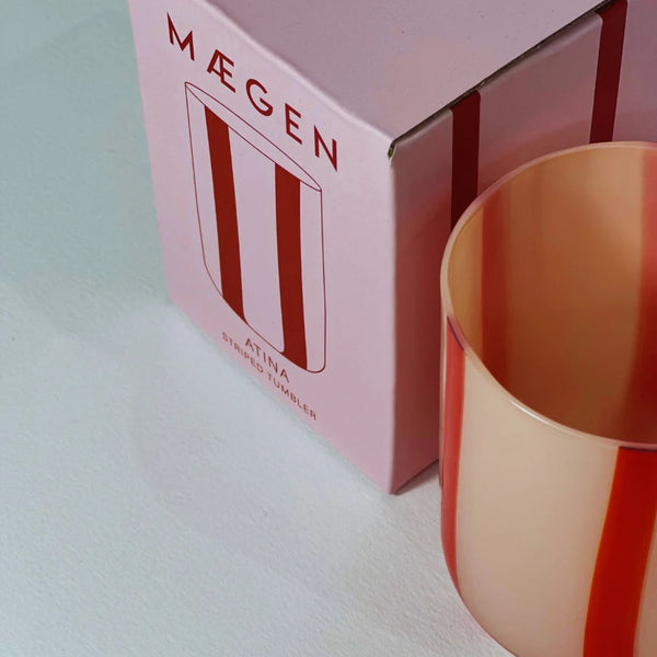 Máegen glass tumbler with pink packaging on a light background