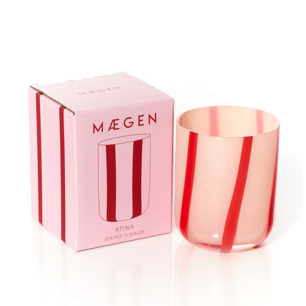Pink striped glass tumbler with Máegen packaging on a white background