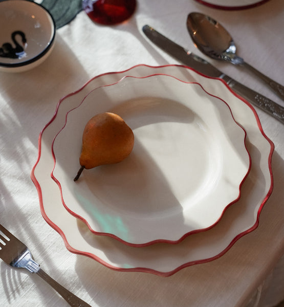 Stacked ceramic  plates with scalloped pink edges.