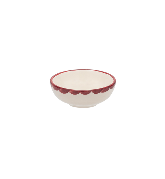Small ceramic bowl with scalloped edge and red rim on a white background
