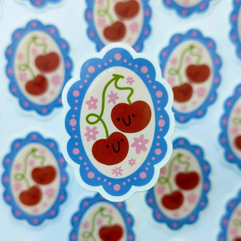 Sticker with cherries and a smiley face on a blue and pink background