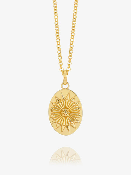 Gold oval pendant with north star design on white background.