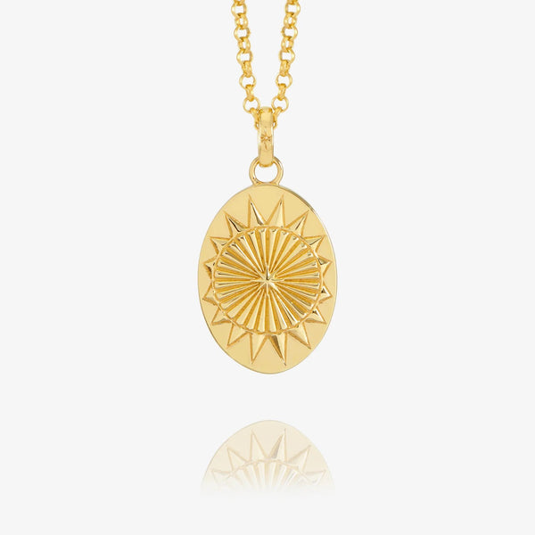 Gold necklace with oval north star design on white background.
