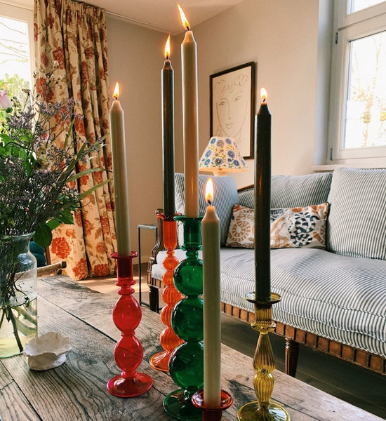 Colorful candle holders with lit candles on a wooden table in a living room.