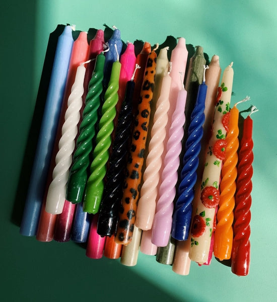 Assorted colorful twisted candles on a green background