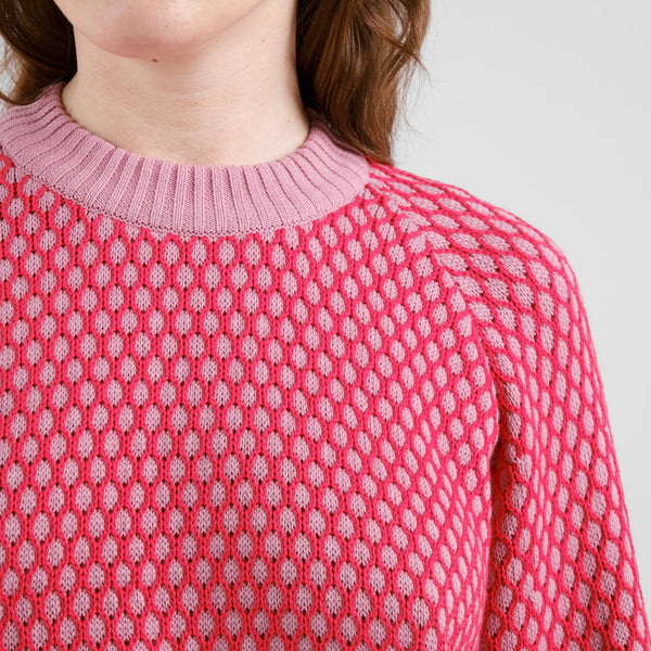 Close-up of a pink bubble knit  textured sweater with a white background
