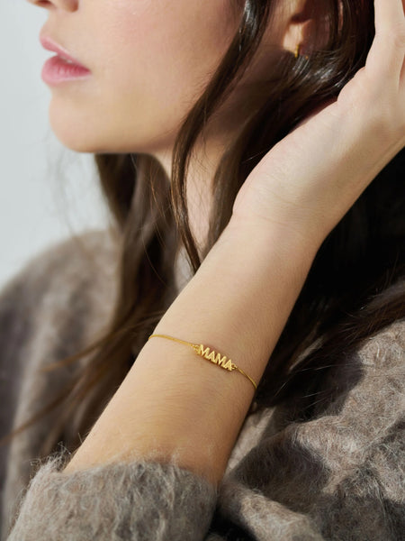 Gold art deco MAMA bracelet on a woman's wrist 
