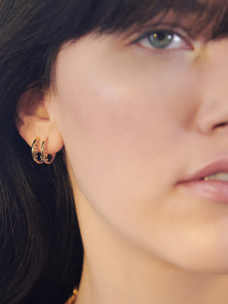 Woman wearing gold orb stellar huggie hoop earrings 