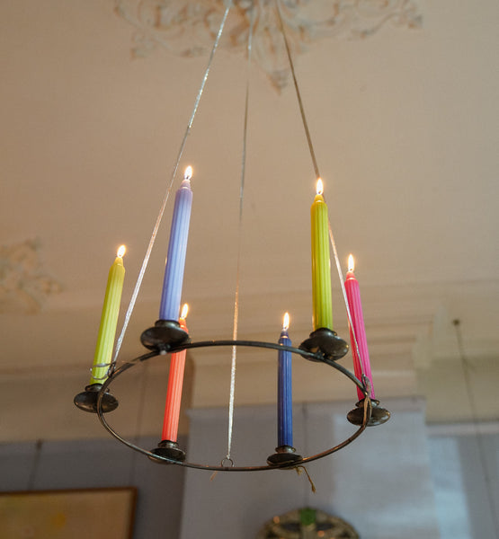 Chandelier with colorful candles against a neutral background