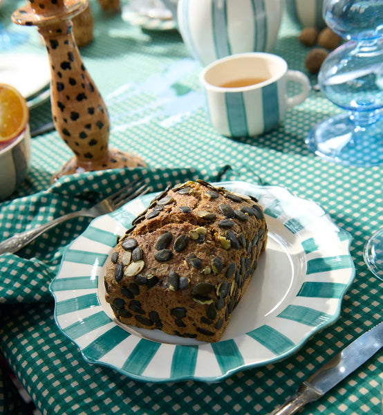 Ceramic plate with scalloped edges in green with a cake on it. 
