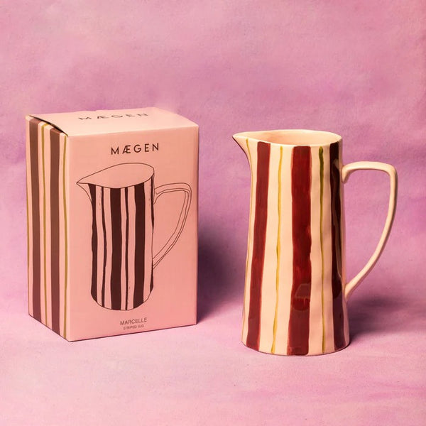 Striped pink and maroon ceramic jug with matching packaging on a pink background