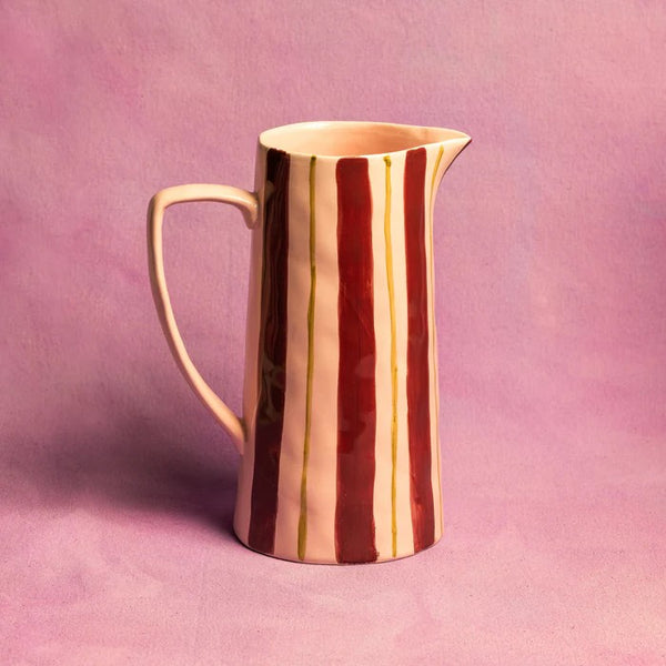 Striped pink and maroon ceramic jug on a pink background