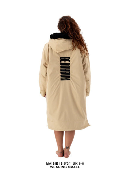 Person wearing a beige robe coat with branding of Beachbum on the back.