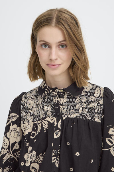 Woman wearing a black blouse with floral embroidery on a white background