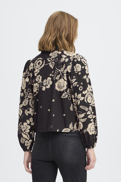 Woman wearing a black floral blouse showing the design on the back 