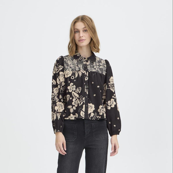 Woman wearing a black floral blouse and black jeans